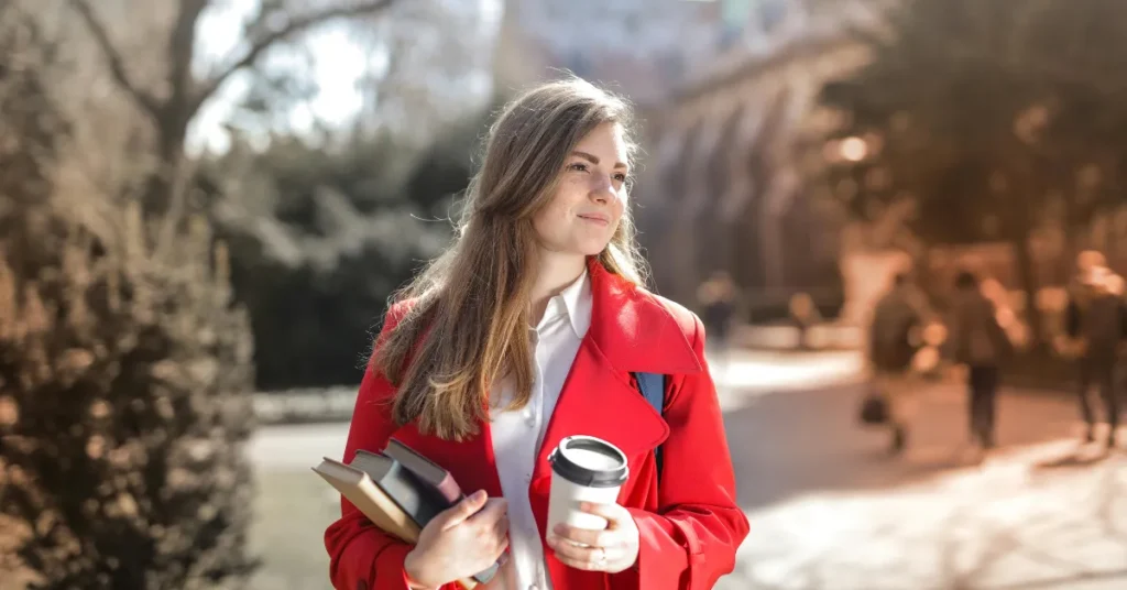 Woman holding a coffee cup and books