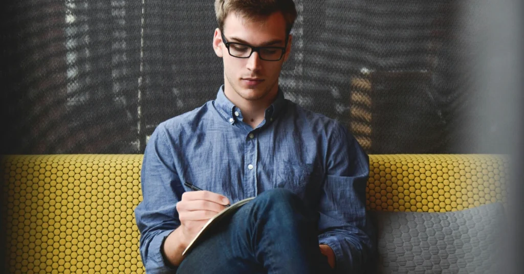 Student Sitting on Chair While Writing Notes