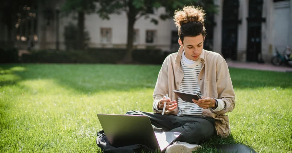 student reading notebook while doing university task