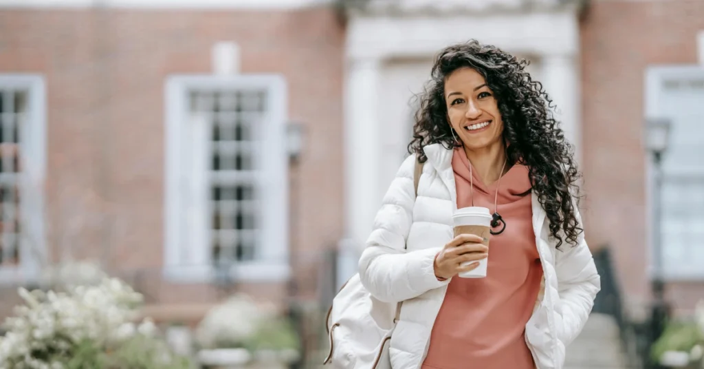 student wearing backpack and drinking takeaway coffee